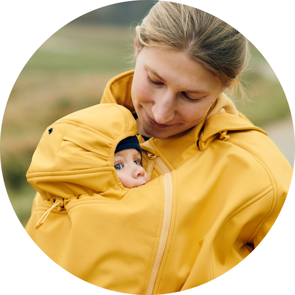 Baby in yellow softshell babywearing jacket with head support, mother looking down lovingly