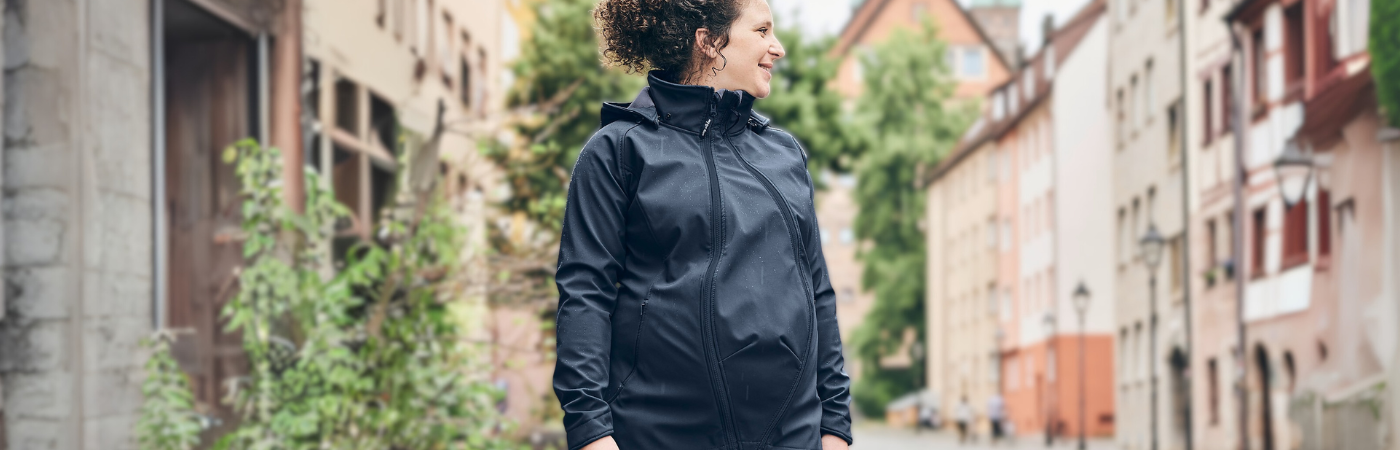 Pregnant woman in dark maternity jacket standing on a city street