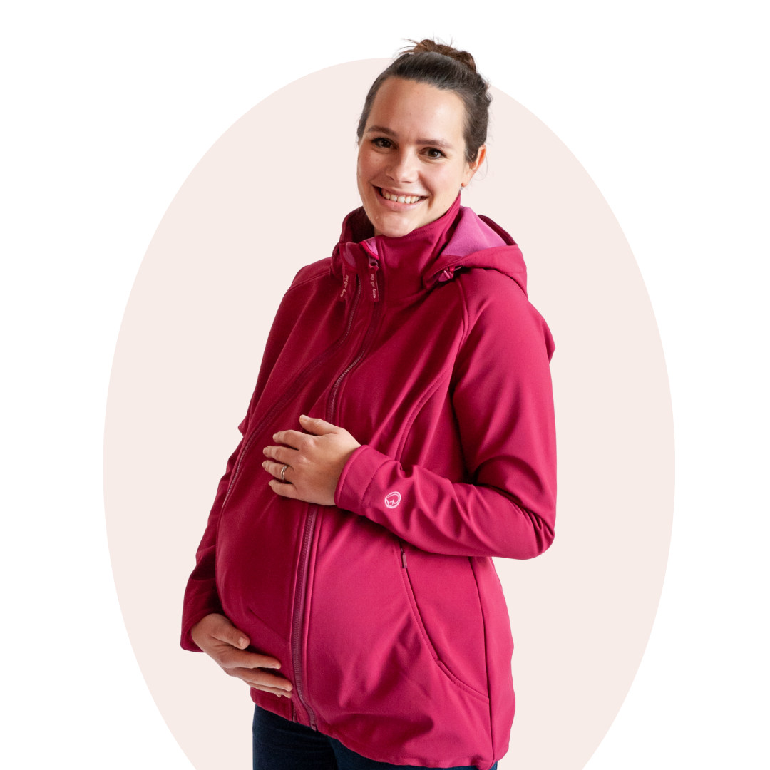 Pregnant woman in pink softshell jacket holding her belly, studio setting